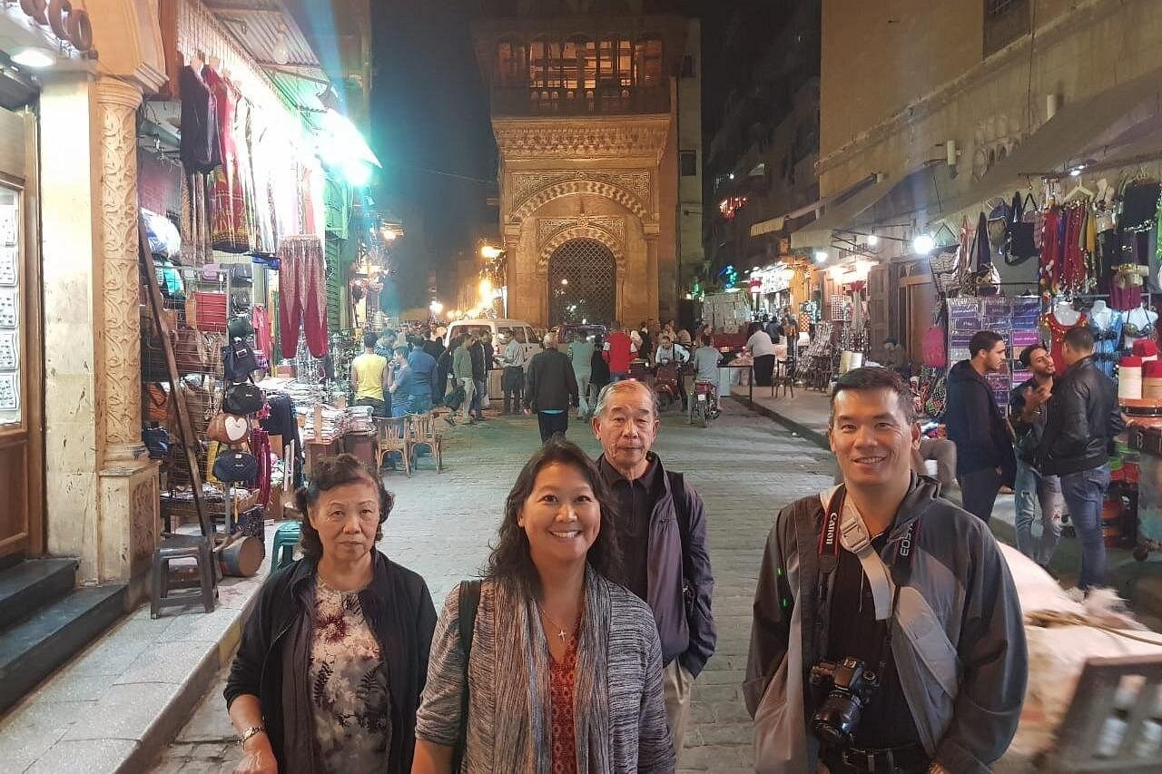 Visitors in a lit historic Cairo market street at night